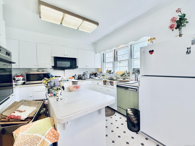 kitchen featuring a kitchen island, light floors, light countertops, white cabinets, and black appliances