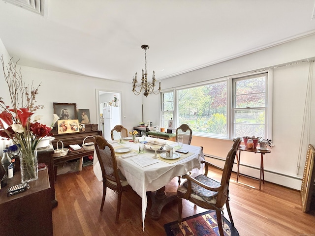 dining space with visible vents, a baseboard heating unit, wood finished floors, and a notable chandelier
