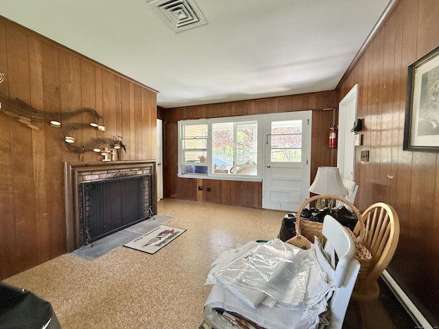 living room featuring visible vents, wood walls, and a fireplace with flush hearth