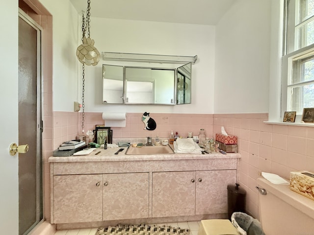 bathroom with vanity, a stall shower, toilet, and tile walls