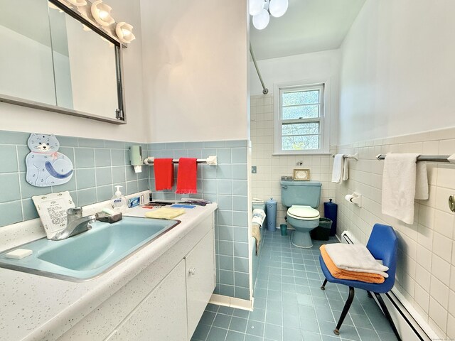 bathroom with tile patterned flooring, wainscoting, toilet, tile walls, and a baseboard radiator