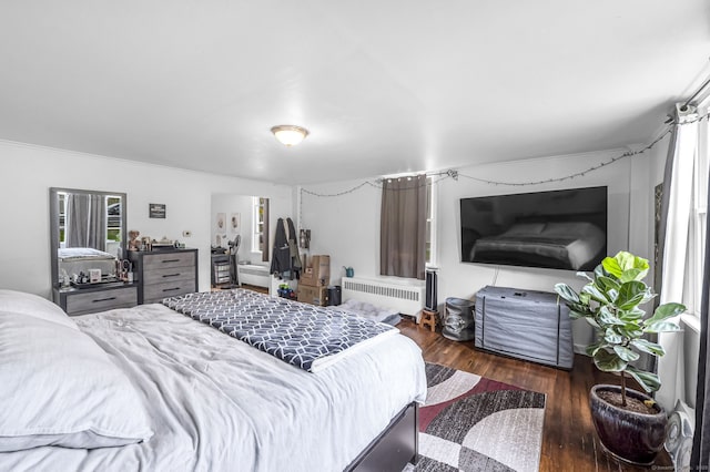 bedroom with radiator heating unit, crown molding, and wood finished floors
