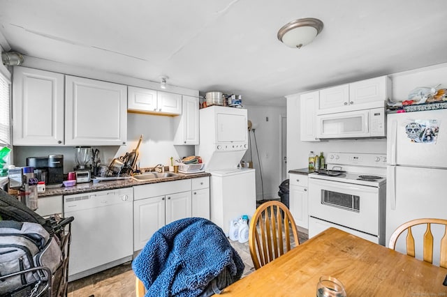 kitchen featuring white cabinets, stacked washer / dryer, and white appliances