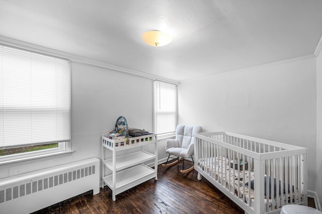 bedroom featuring wood-type flooring, ornamental molding, radiator heating unit, and multiple windows