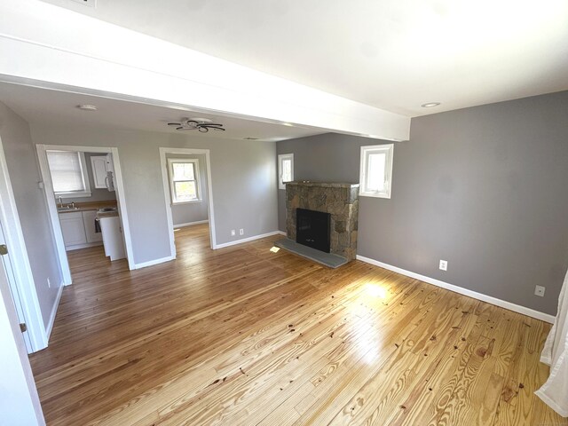 6 Fulton Dr, New Fairfield, CT 06812 - unfurnished living room featuring baseboards, a sink, wood finished floors, and a stone fireplace