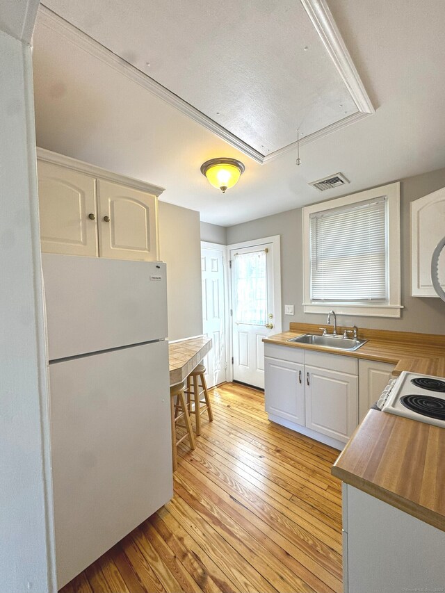 6 Fulton Dr, New Fairfield, CT 06812 - kitchen featuring visible vents, freestanding refrigerator, white cabinetry, a sink, and light wood finished floors