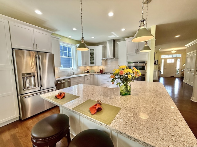 kitchen with plenty of natural light, a sink, wall chimney exhaust hood, and appliances with stainless steel finishes
