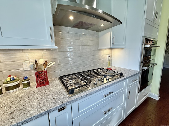 kitchen featuring decorative backsplash, dark wood-style floors, ventilation hood, white cabinetry, and appliances with stainless steel finishes