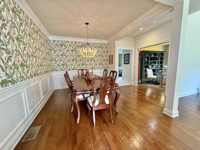 dining area featuring visible vents, crown molding, wainscoting, wood finished floors, and a chandelier