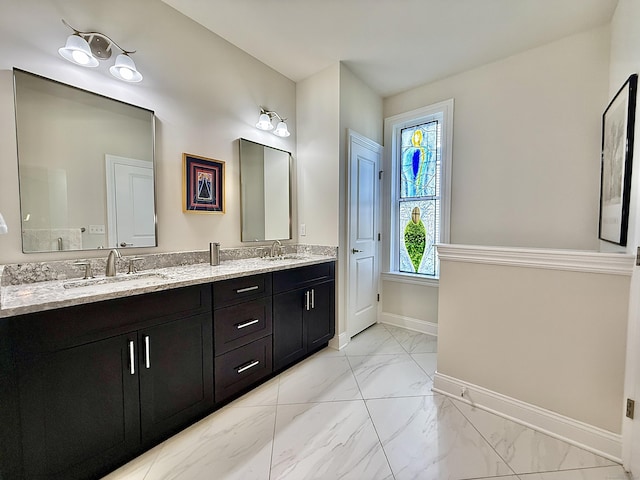 full bathroom with baseboards, a sink, marble finish floor, and double vanity