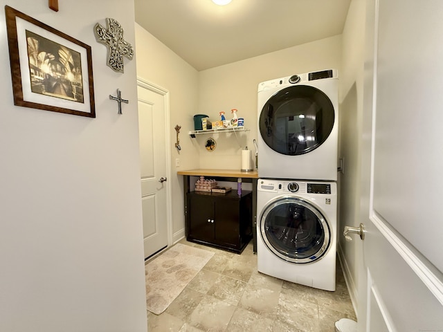 laundry room with stacked washing maching and dryer, baseboards, laundry area, and stone finish flooring