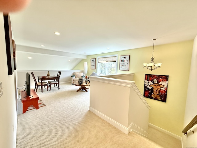 corridor featuring vaulted ceiling, baseboards, an upstairs landing, an inviting chandelier, and light carpet
