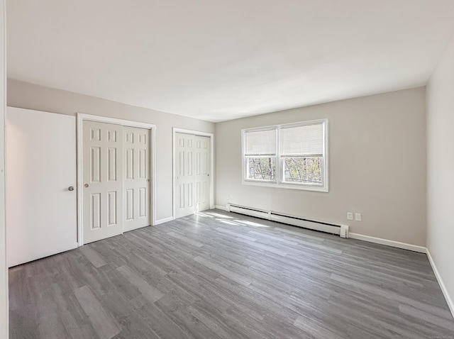 139 Downes St Unit 139, Waterbury, CT 06704 - unfurnished bedroom featuring multiple closets, a baseboard radiator, baseboards, and wood finished floors