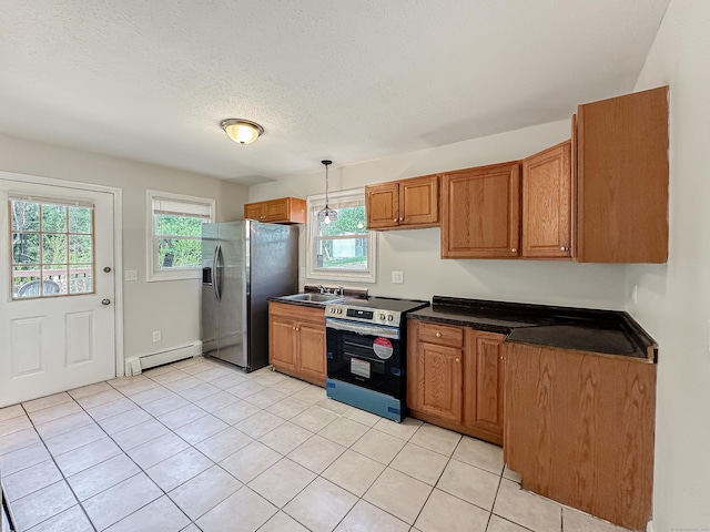 139 Downes St Unit 139, Waterbury, CT 06704 - kitchen with light tile patterned flooring, dark countertops, baseboard heating, brown cabinetry, and stainless steel appliances