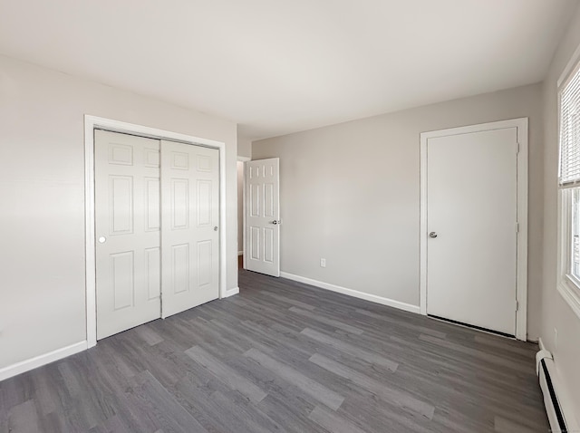 139 Downes St Unit 139, Waterbury, CT 06704 - unfurnished bedroom featuring baseboards, baseboard heating, a closet, and dark wood-style floors