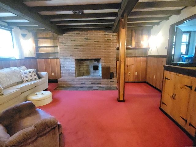 carpeted living room featuring wood walls, wainscoting, a fireplace, and beamed ceiling