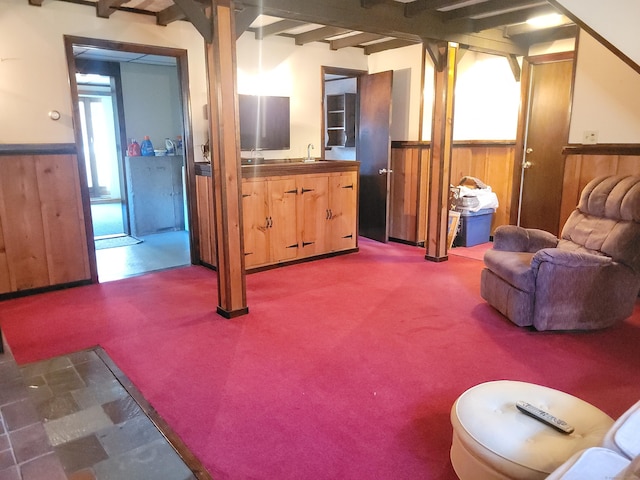 carpeted living area with beamed ceiling, wainscoting, and a wealth of natural light