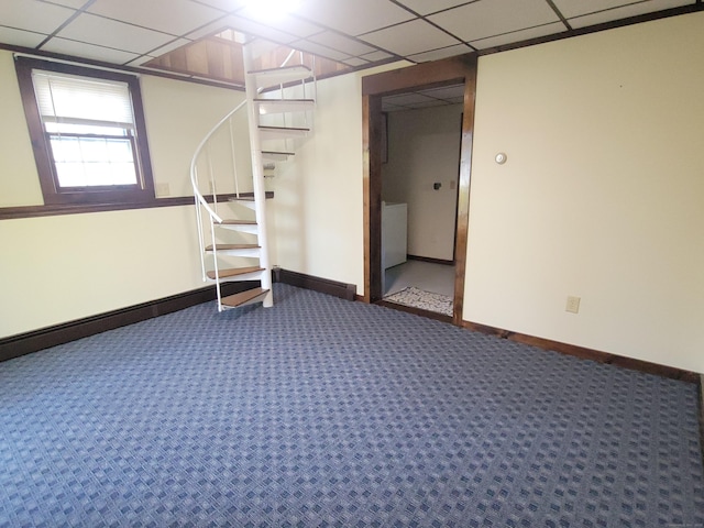 below grade area with carpet floors, baseboards, and a drop ceiling