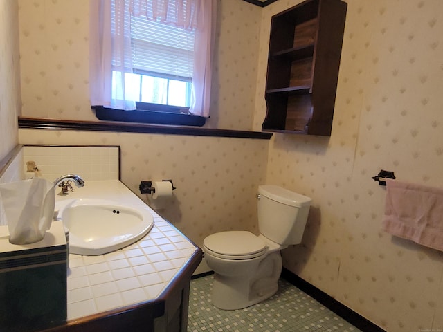 bathroom with vanity, toilet, and wallpapered walls