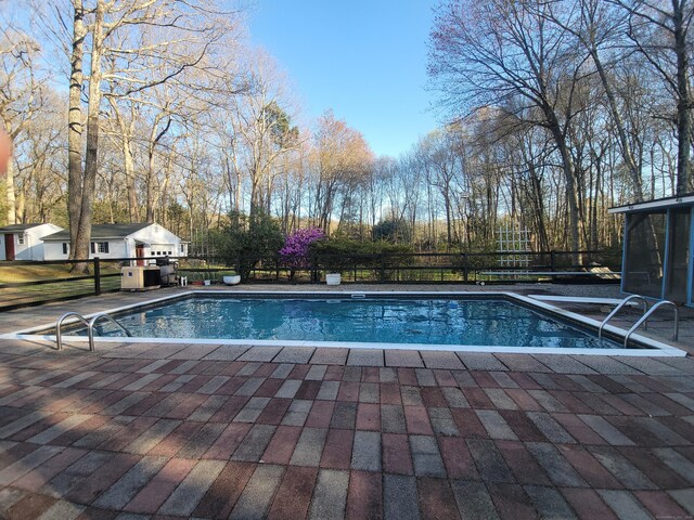 outdoor pool featuring fence and a patio