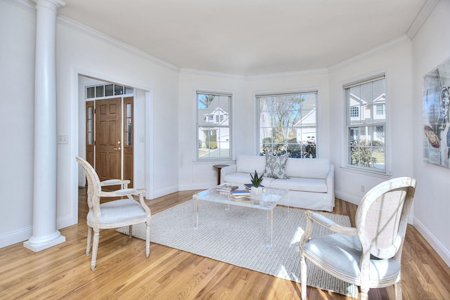 interior space featuring ornate columns, ornamental molding, light wood-style flooring, and baseboards