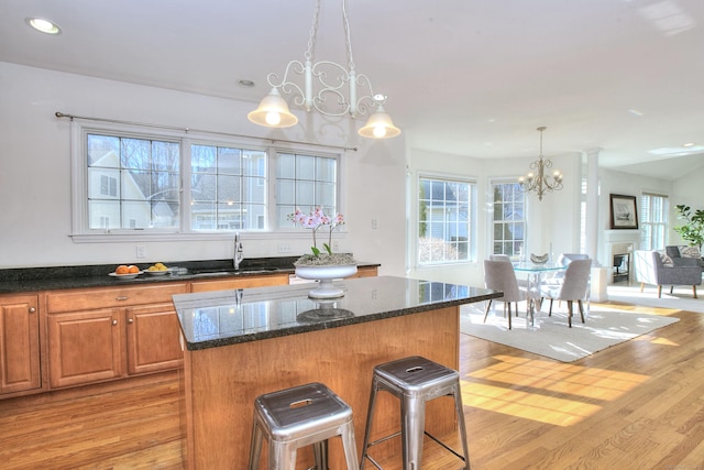 kitchen featuring an inviting chandelier, a wealth of natural light, a sink, and a center island