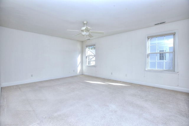 unfurnished room featuring baseboards, ceiling fan, visible vents, and light colored carpet