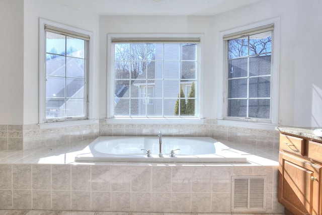 bathroom featuring a healthy amount of sunlight, a bath, and visible vents