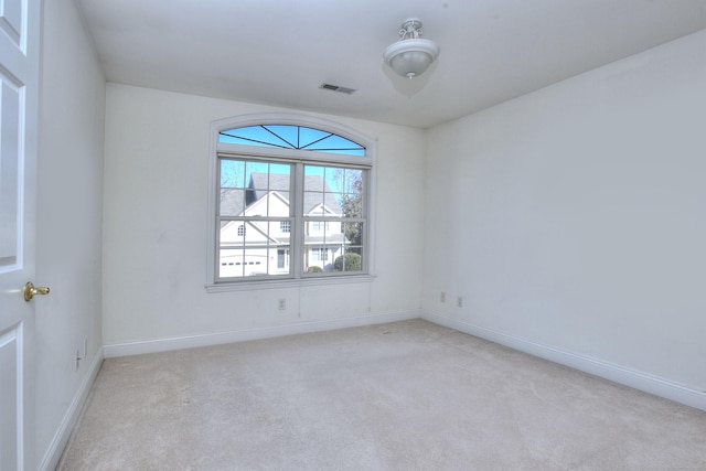 unfurnished room featuring baseboards, visible vents, and light carpet
