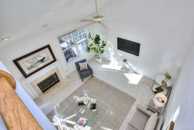 carpeted living area featuring a ceiling fan and a fireplace