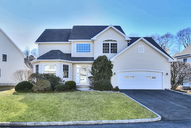 traditional-style house featuring roof with shingles, an attached garage, a front lawn, and aphalt driveway