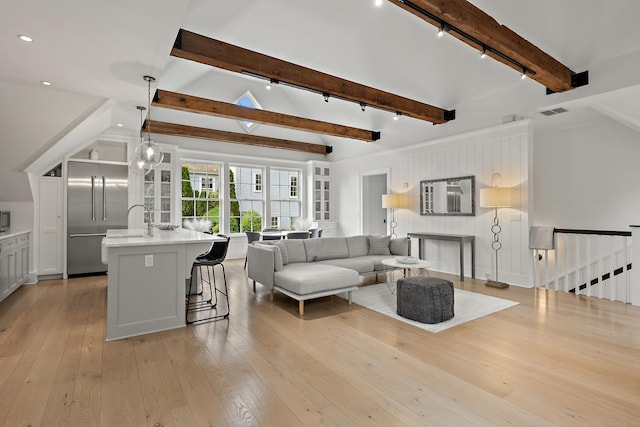 living room featuring visible vents, rail lighting, light wood-style flooring, and beam ceiling