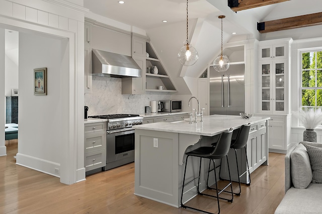 kitchen with a kitchen bar, high end appliances, tasteful backsplash, ventilation hood, and light wood-style floors