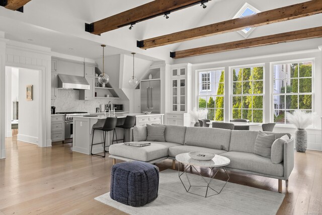 living area with light wood-style floors, lofted ceiling with beams, and rail lighting