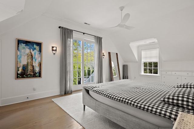 bedroom with light wood-type flooring, baseboards, vaulted ceiling, and multiple windows