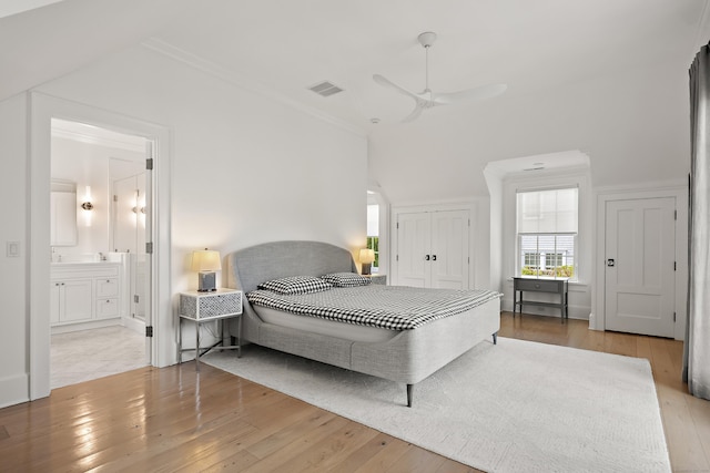 bedroom featuring visible vents, connected bathroom, light wood-style floors, and crown molding