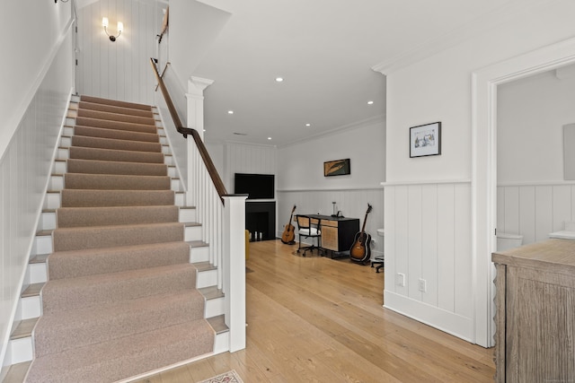 stairs featuring crown molding, recessed lighting, hardwood / wood-style flooring, and a wainscoted wall