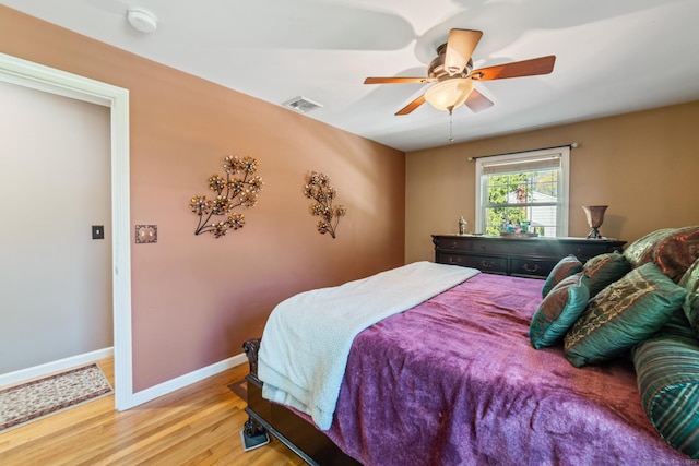 bedroom with visible vents, a ceiling fan, light wood finished floors, and baseboards