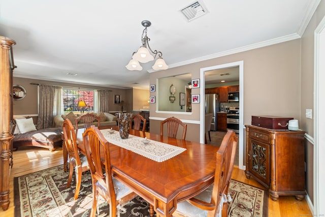 dining room featuring crown molding, light wood-style flooring, and visible vents