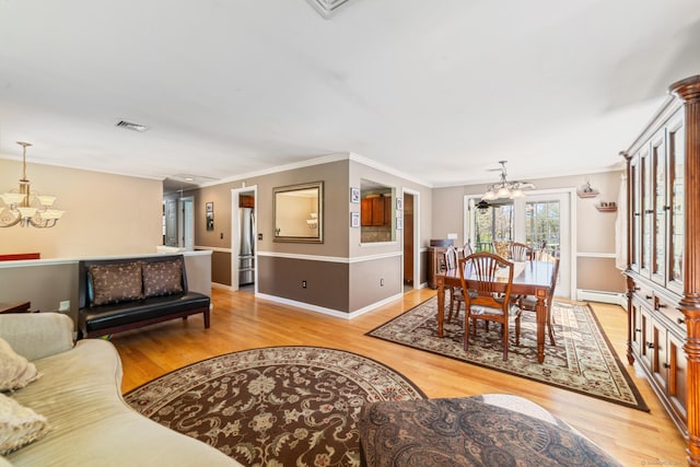 living area with an inviting chandelier, light wood finished floors, a baseboard heating unit, and visible vents