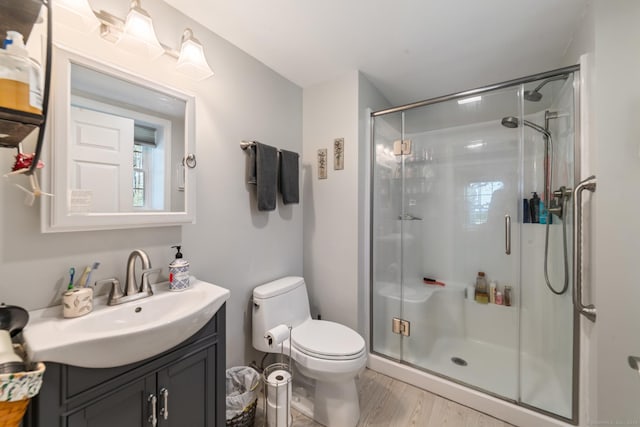 bathroom with vanity, a stall shower, toilet, and wood finished floors