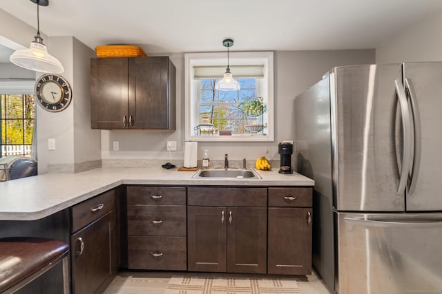 kitchen featuring freestanding refrigerator, a sink, dark brown cabinets, and light countertops