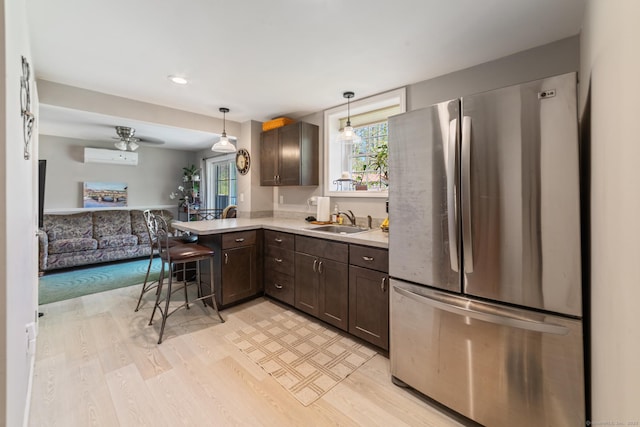 kitchen featuring dark brown cabinetry, light wood-type flooring, a sink, freestanding refrigerator, and open floor plan