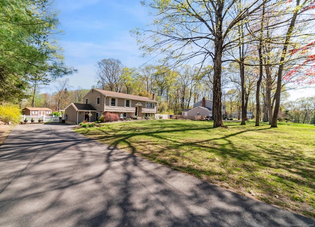 view of front of home featuring fence, a front lawn, and aphalt driveway