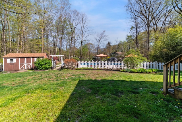 view of yard featuring fence, a pool, an outbuilding, and a shed
