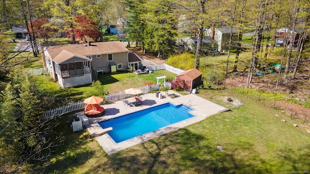 view of pool featuring an outdoor structure, a fenced backyard, a sunroom, a fenced in pool, and a lawn