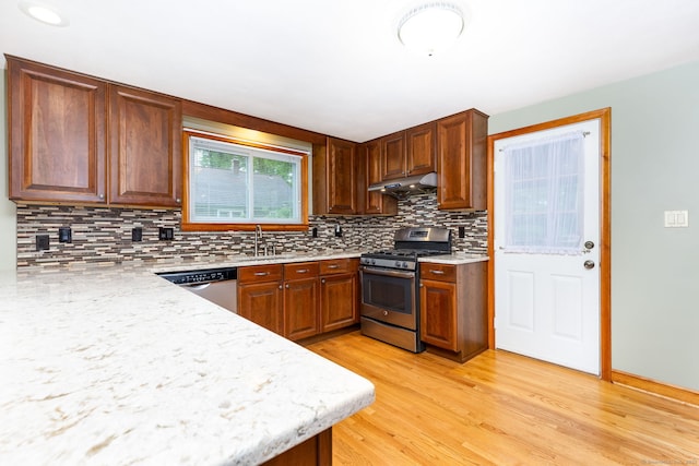 kitchen with light countertops, appliances with stainless steel finishes, light wood-style flooring, and tasteful backsplash