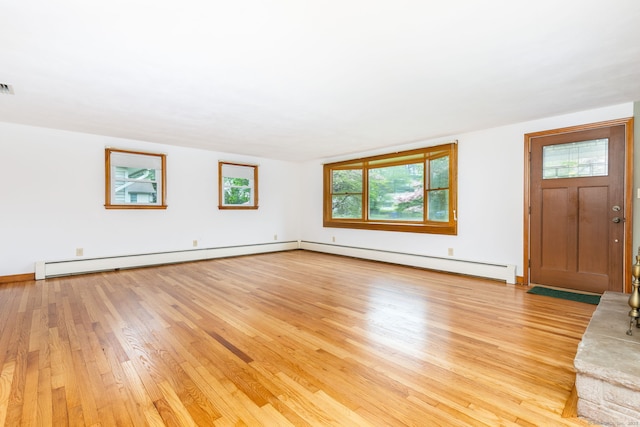 unfurnished living room with baseboard heating, light wood finished floors, and visible vents