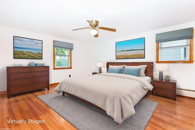bedroom with light wood-type flooring, a ceiling fan, and a baseboard heating unit
