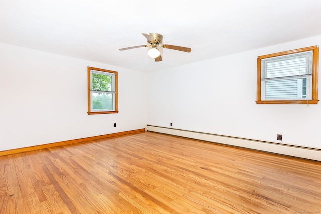 spare room with a ceiling fan, baseboards, baseboard heating, and light wood-type flooring